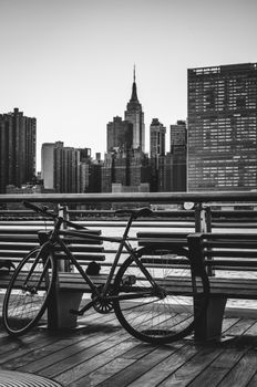 纽约市天际线的单色图像中，木板路上停着一辆自行车