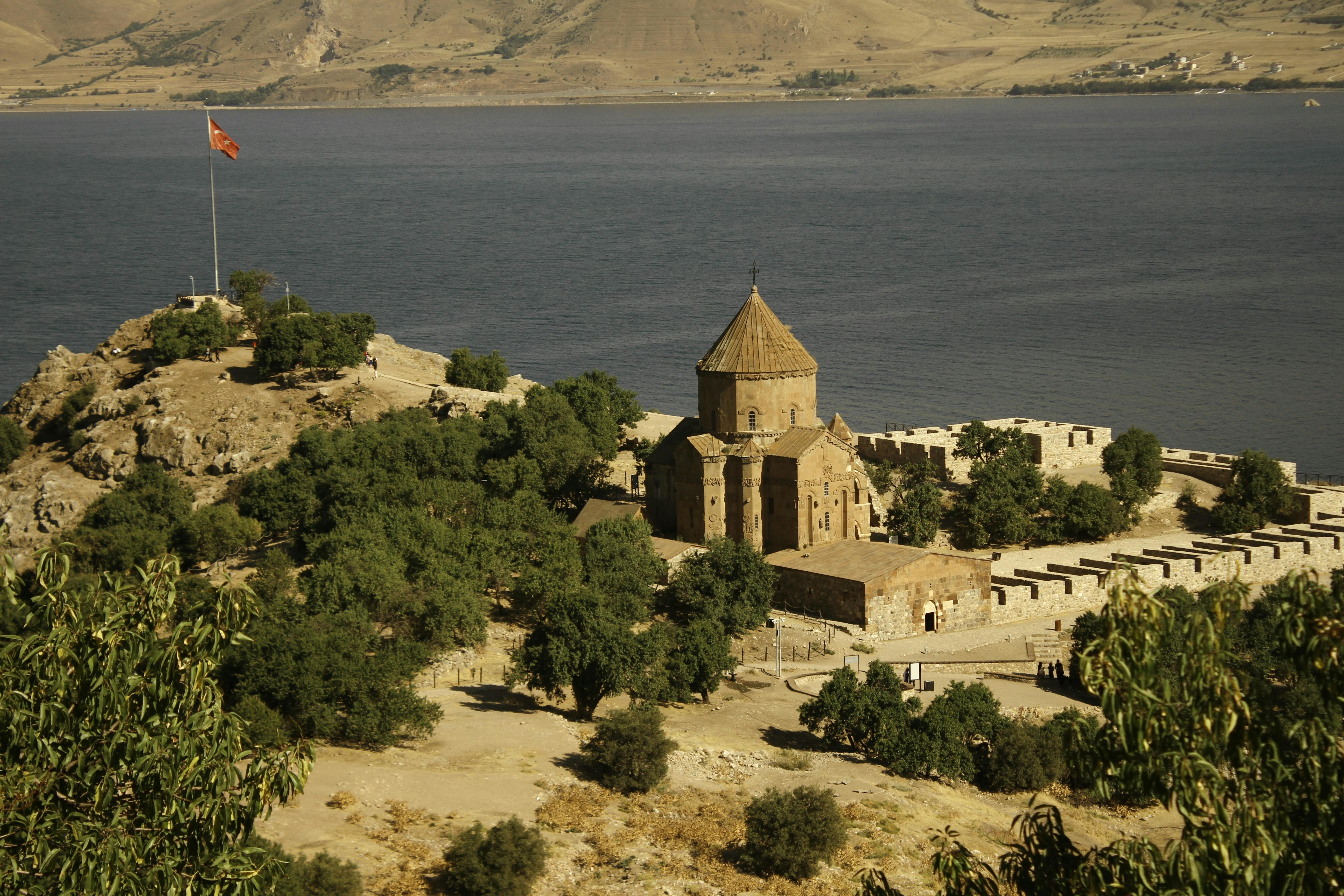 Medieval Armenian Church of the Holy Cross on Akdamar Island at golden hour, Lake Van, eastern Turkey, intricate stone carvings against turquoise water