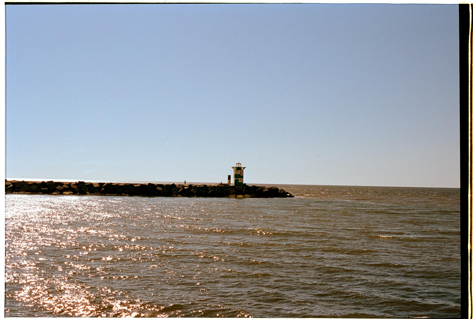Peaceful scene of a lighthouse by the sea in The Hague under clear skies.