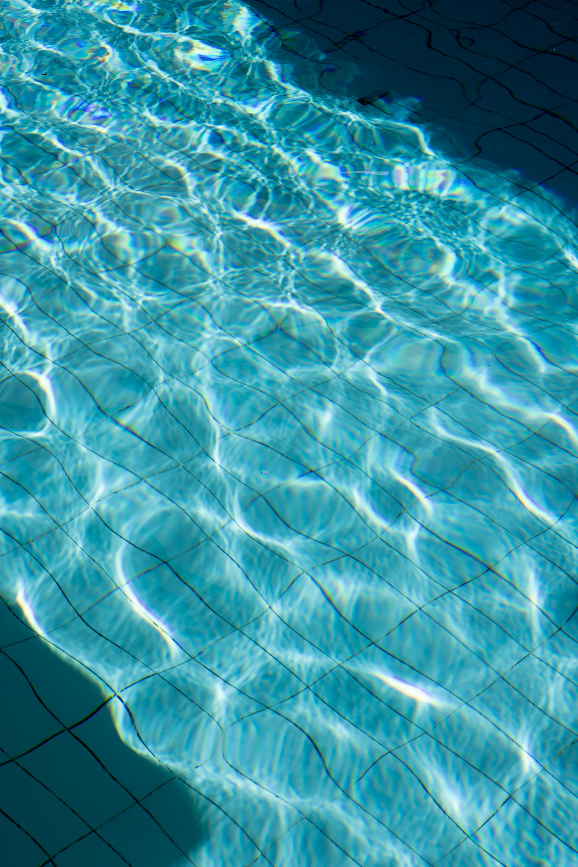 Sunlit ripples create a mesmerizing pattern in a clear pool, capturing light reflections.