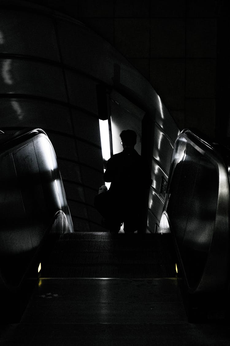 Black And White Abstract Image Of A Man On An Underground Escalator