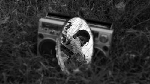 Reflection of Woman with Twigs in Mirror on Grass