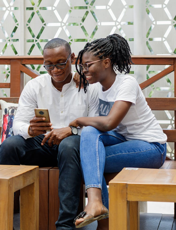 Young Couple Looking At A Smartphone And Smiling 