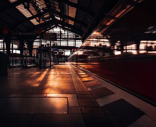 Free Dramatic sunset view of a train station in Berlin with a moving train and warm lighting. Stock Photo