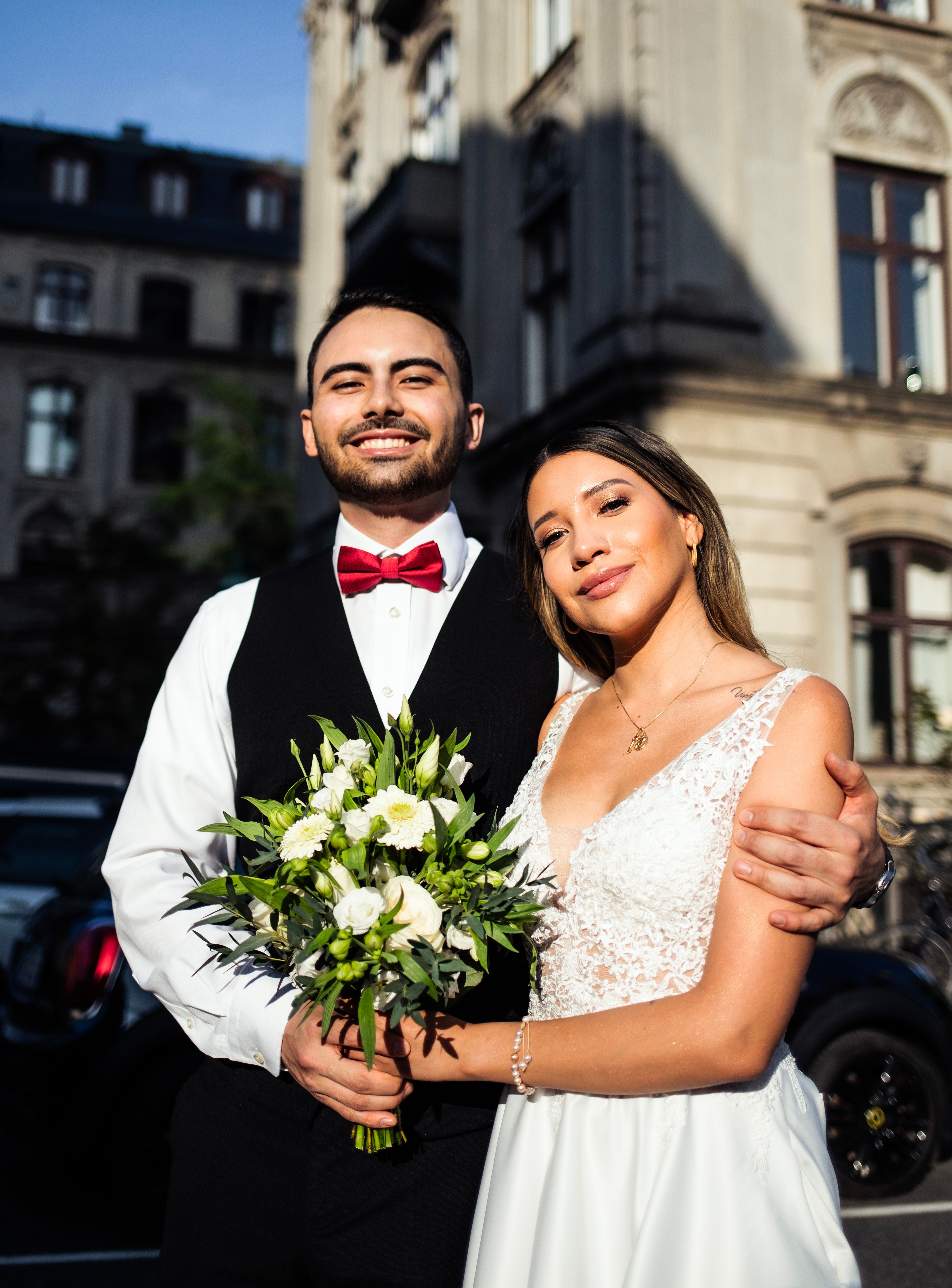 A bride and groom pose for a photo in front of a building · Free Stock ...