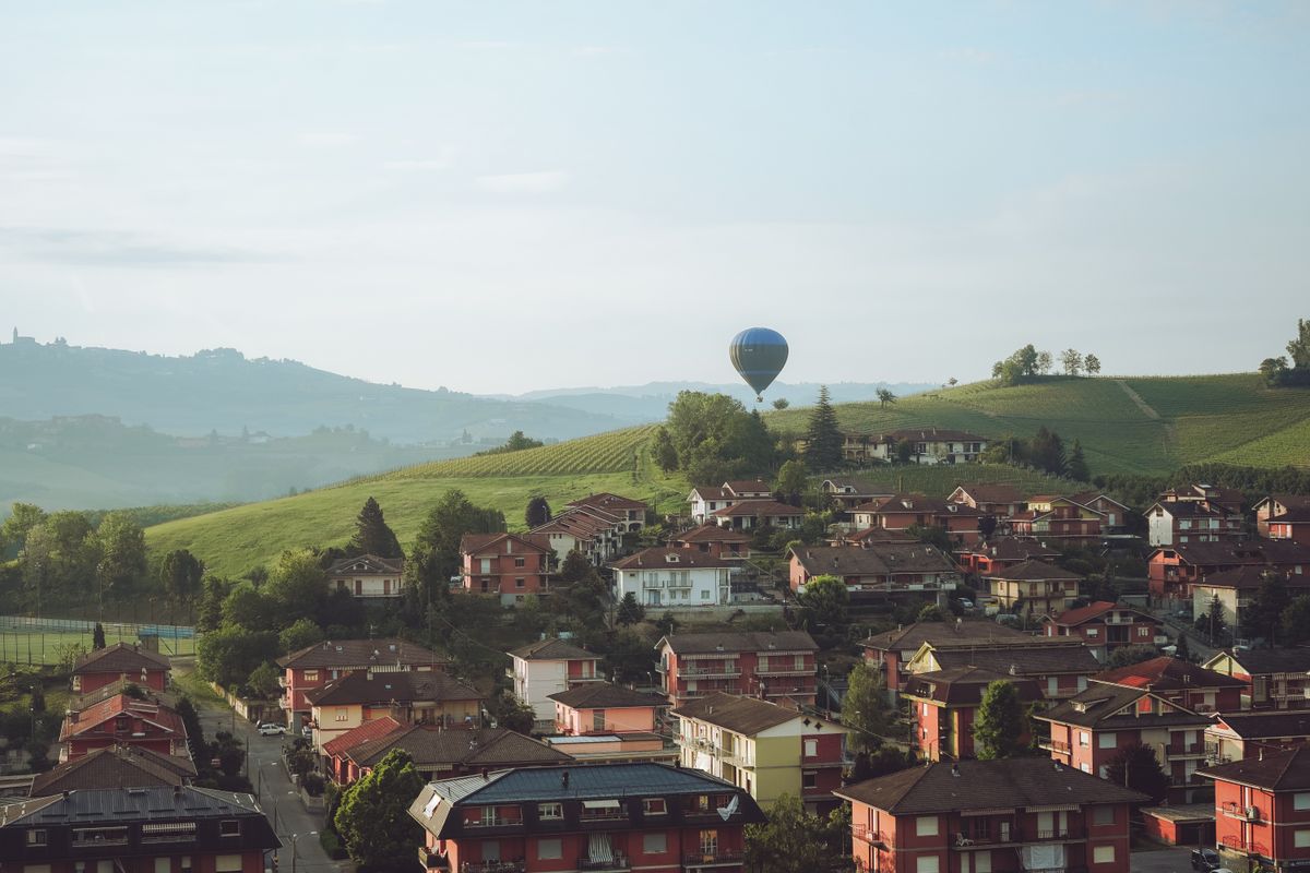 Balon cu aer cald deasupra satului Barolo si a dealurilor verzi