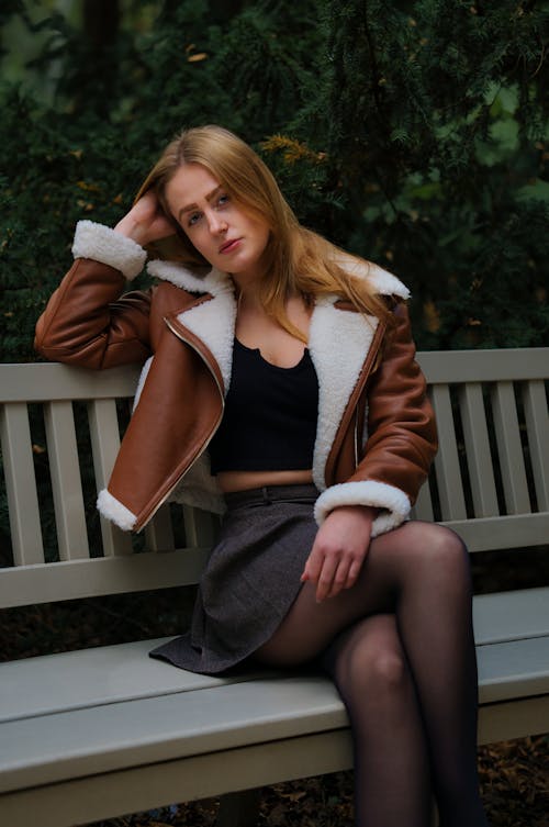 Woman in Jacket and Skirt Posing on Bench
