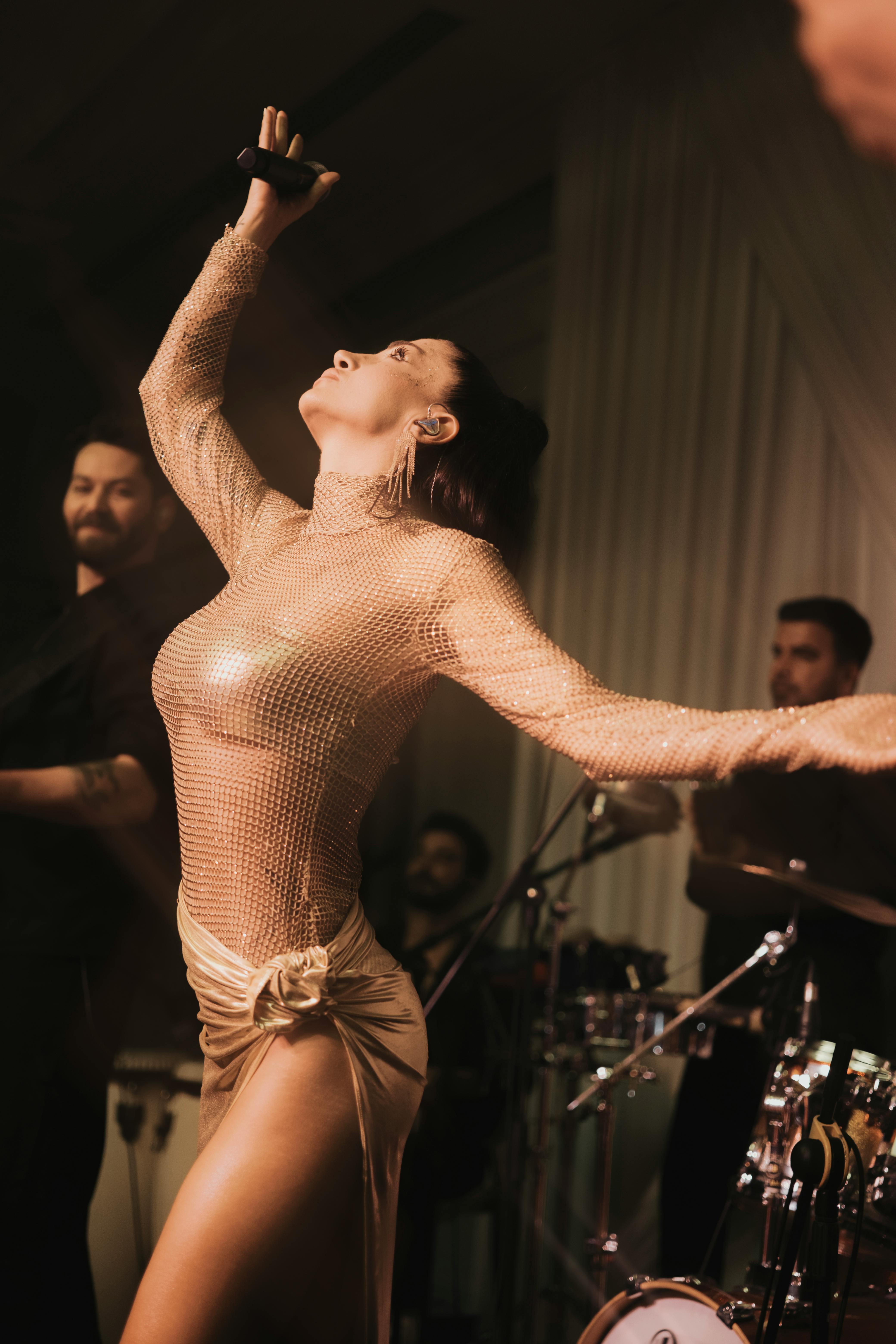 a woman in a gold dress singing on stage