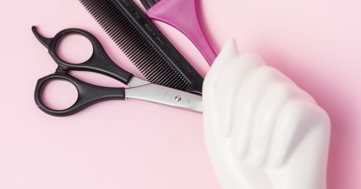 A hand holding a pair of scissors and a pair of hair curlers
