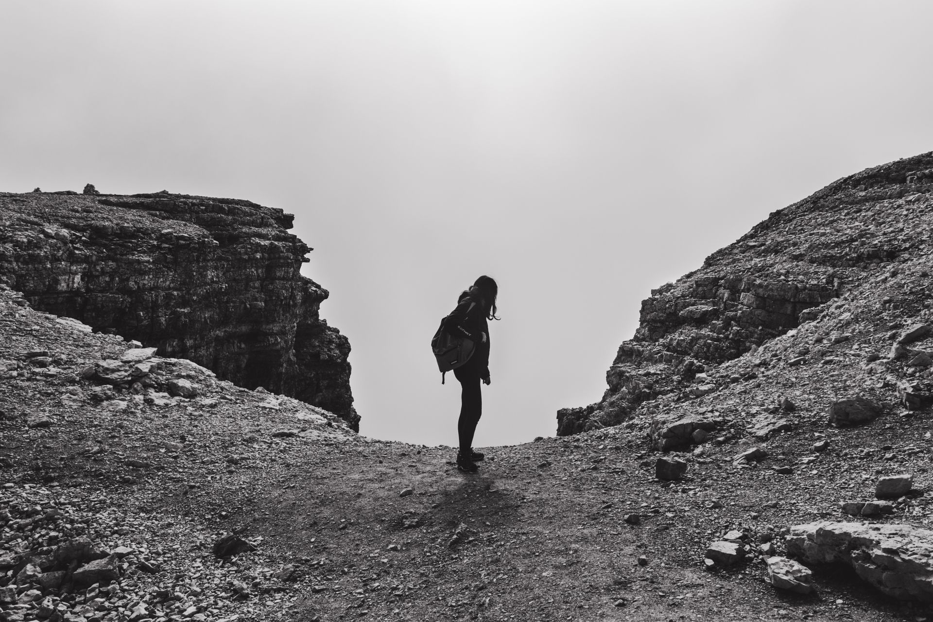 Hiker Looking into the Abyss from the Edge of a Rock
