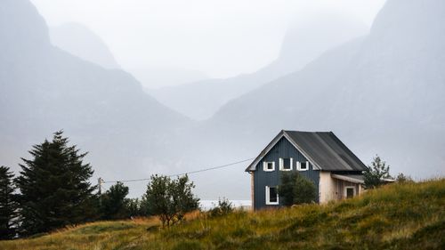 Free A picturesque wooden cabin amidst misty Nordic mountains and lush greenery in fall. Stock Photo