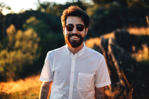 Free Portrait of a bearded man in sunglasses smiling outdoors with sunlight and natural background. Stock Photo