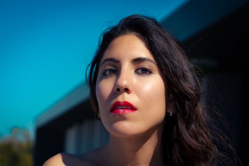 Free Stunning close-up portrait of a woman with black hair and vibrant red lipstick, captured outdoors. Stock Photo