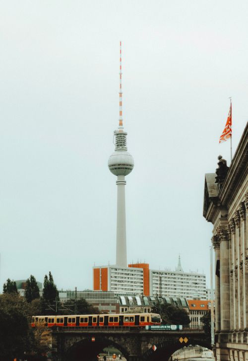 Free View of Berlin's iconic Fernsehturm with a train passing by, capturing urban life. Stock Photo