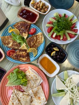 An appetizing overhead view of a colorful Middle Eastern breakfast spread featuring fresh vegetables, cheese, and pancakes.