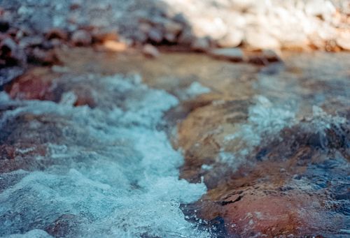 Free Close-up of a serene stream flowing over rocks at Radium Hot Springs, perfect nature background. Stock Photo