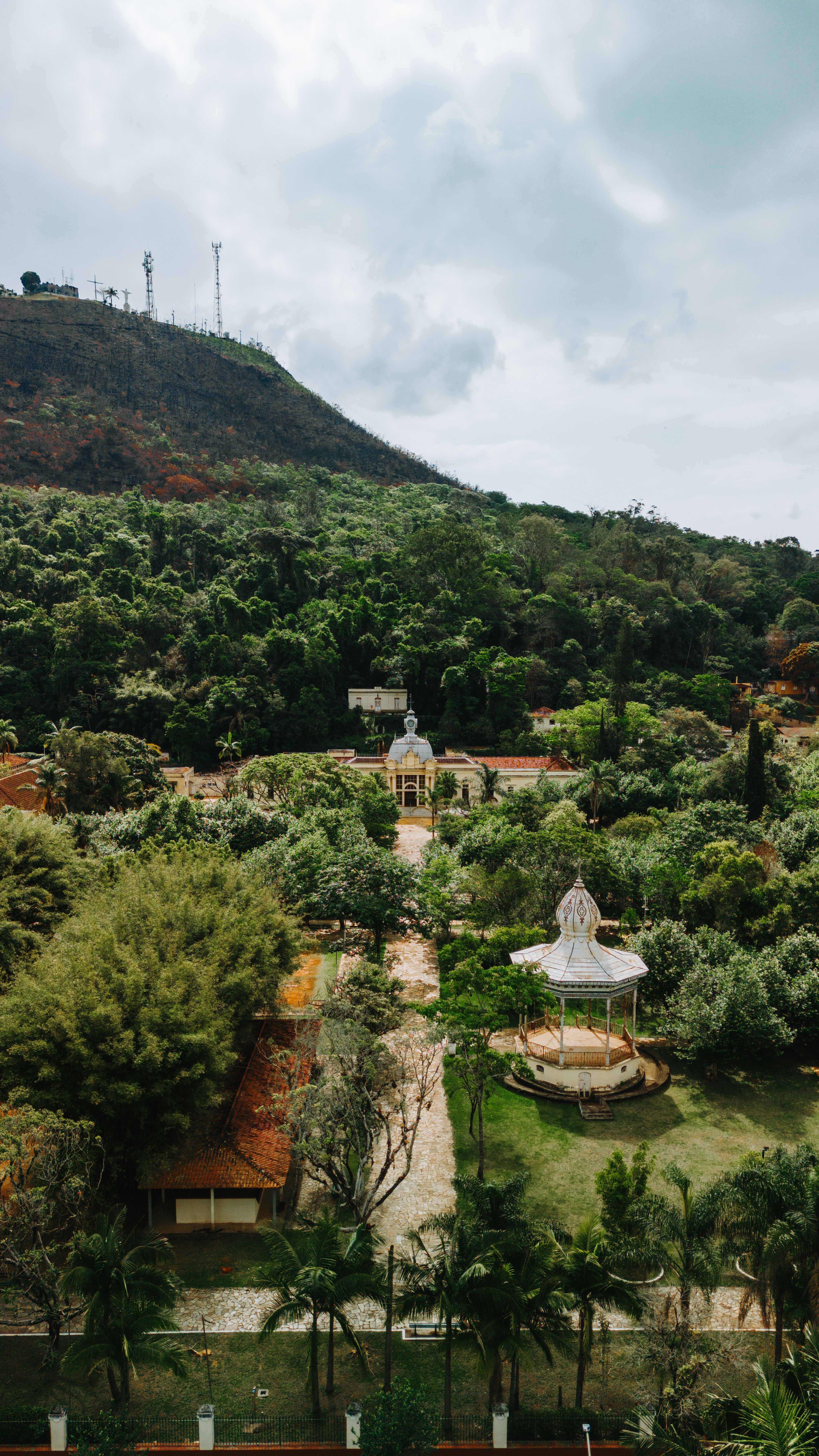 Fotomural Vista aérea de un parque exuberante en Caxambu, Brasil, con gazebos y colinas.