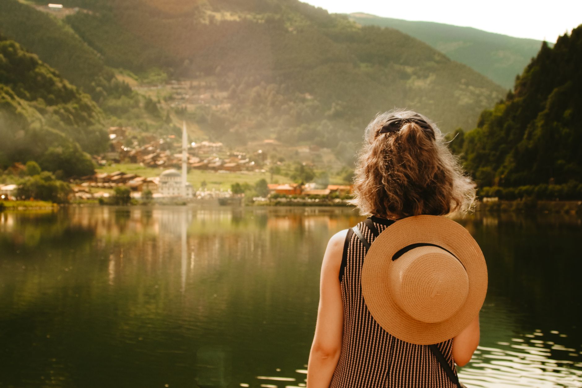 Tourist admiring Uzungöl Lake in summer, set against breathtaking mountain landscape in Turkey.
