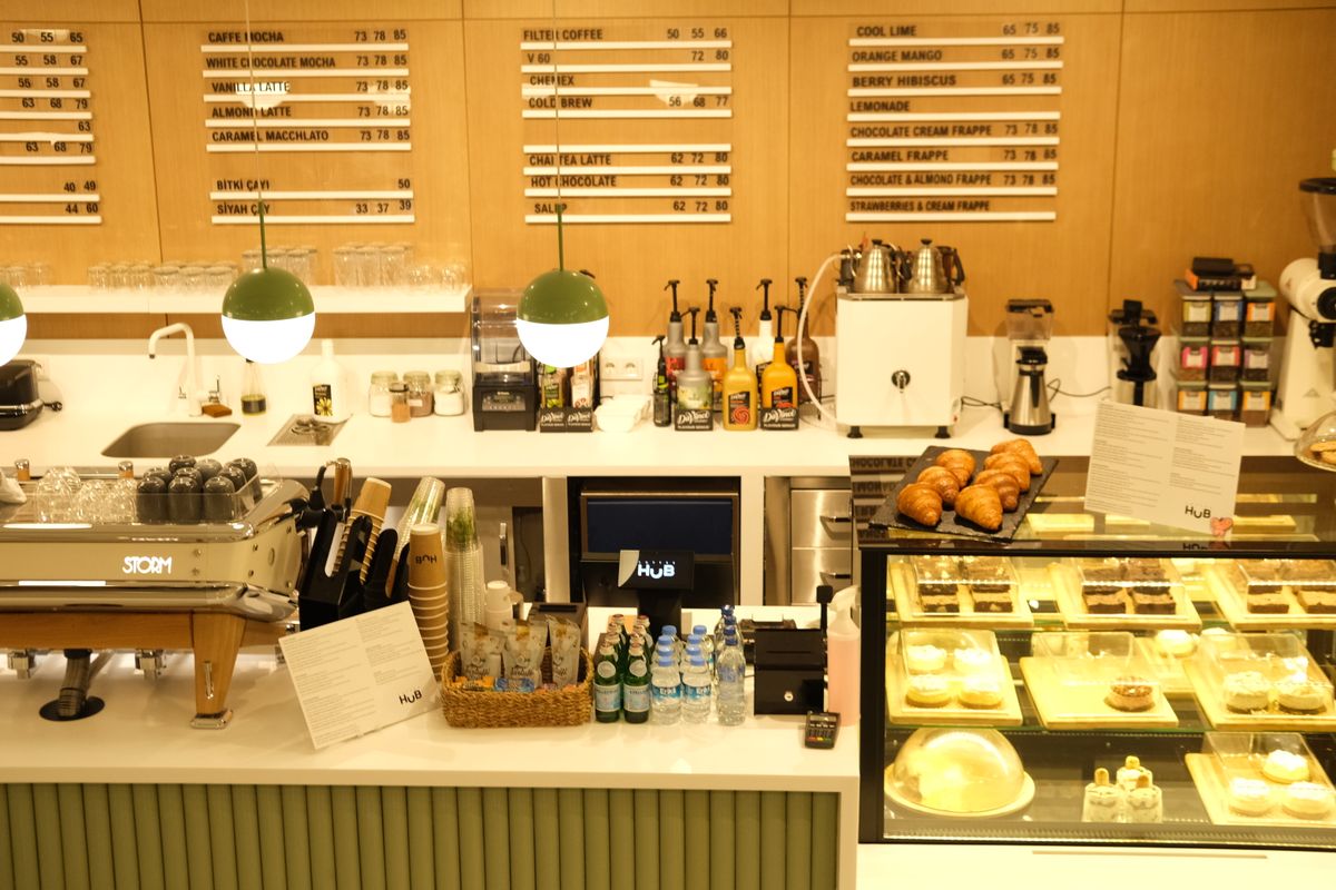 A warm café counter with pastries and a menu board.