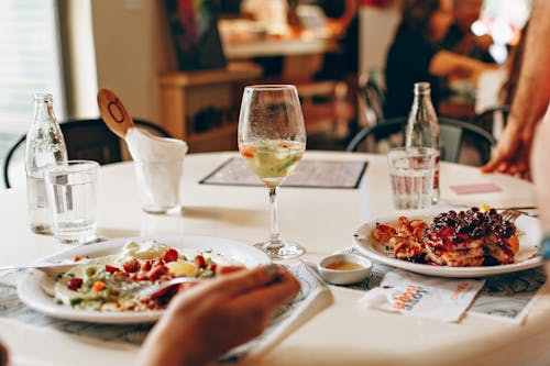 Gratis Anggur Di Gelas Bening Dekat Makanan Di Piring Di Atas Meja Foto Stok