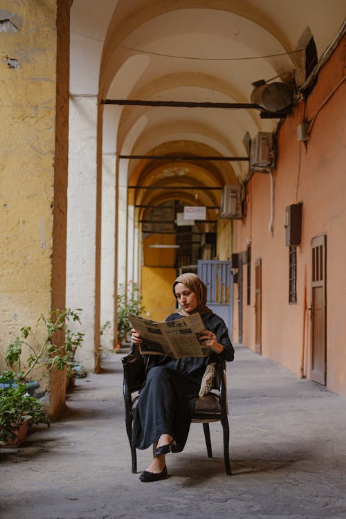 Gratis stockfoto met arabische vrouw, hijab, in kleermakerszit