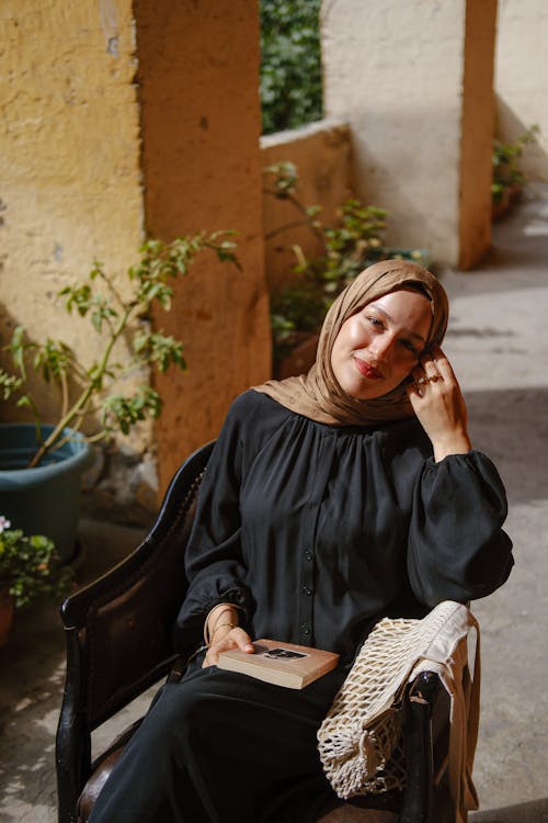 A woman in a black hijab sitting on a chair