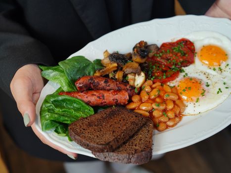A delicious breakfast plate featuring eggs, sausages, beans, toast, and fresh vegetables.