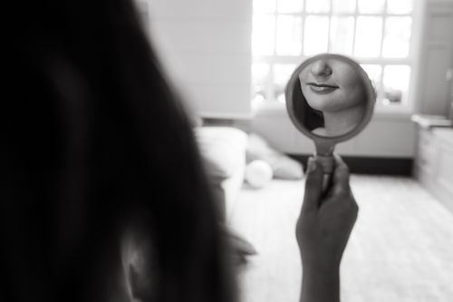 Woman's face reflected in a hand mirror, black and white