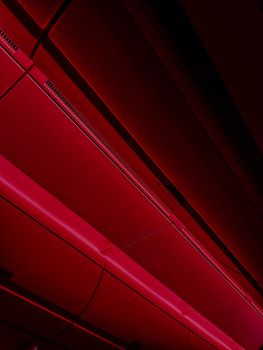 Abstract view of a red LED-lit ceiling with geometric lines and shadows.