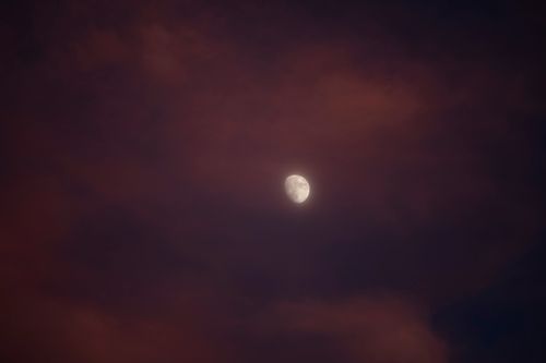 Free A moody evening sky showcasing a waxing gibbous moon amidst dusky clouds. Stock Photo