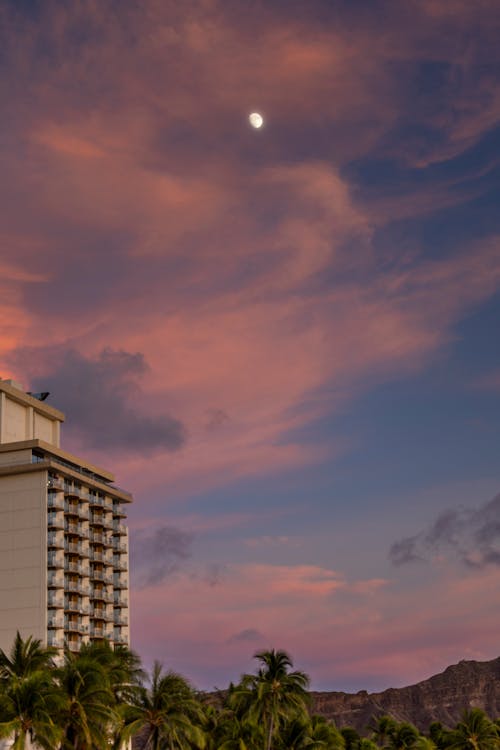 Moon behind Clouds over Building at Dusk