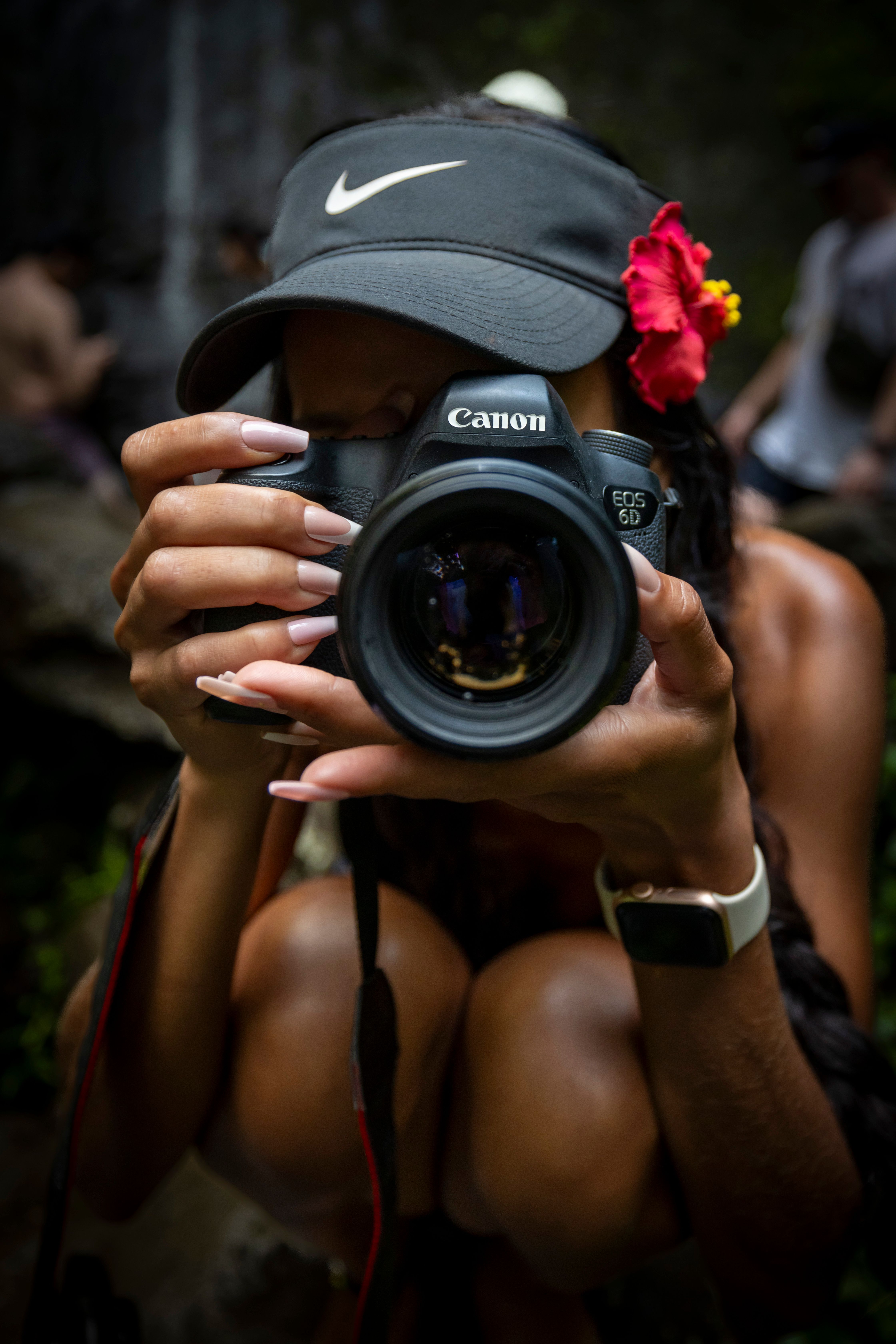 Woman photographer squatting, focusing and taking a picture outdoors with a Canon camera.