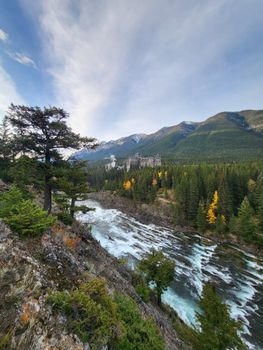 Breathtaking view of a flowing river through autumn forests with distant mountains.