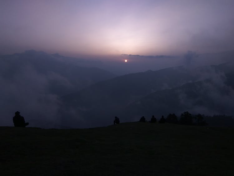 People Sitting On Hills At Dusk