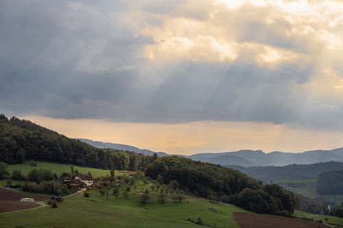Free Scenic rural landscape with sunbeams over a village during sunset. Stock Photo