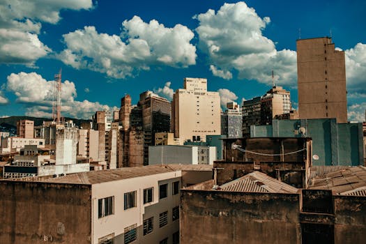 City skyline featuring a mix of old and modern buildings under a vibrant blue sky with clouds.