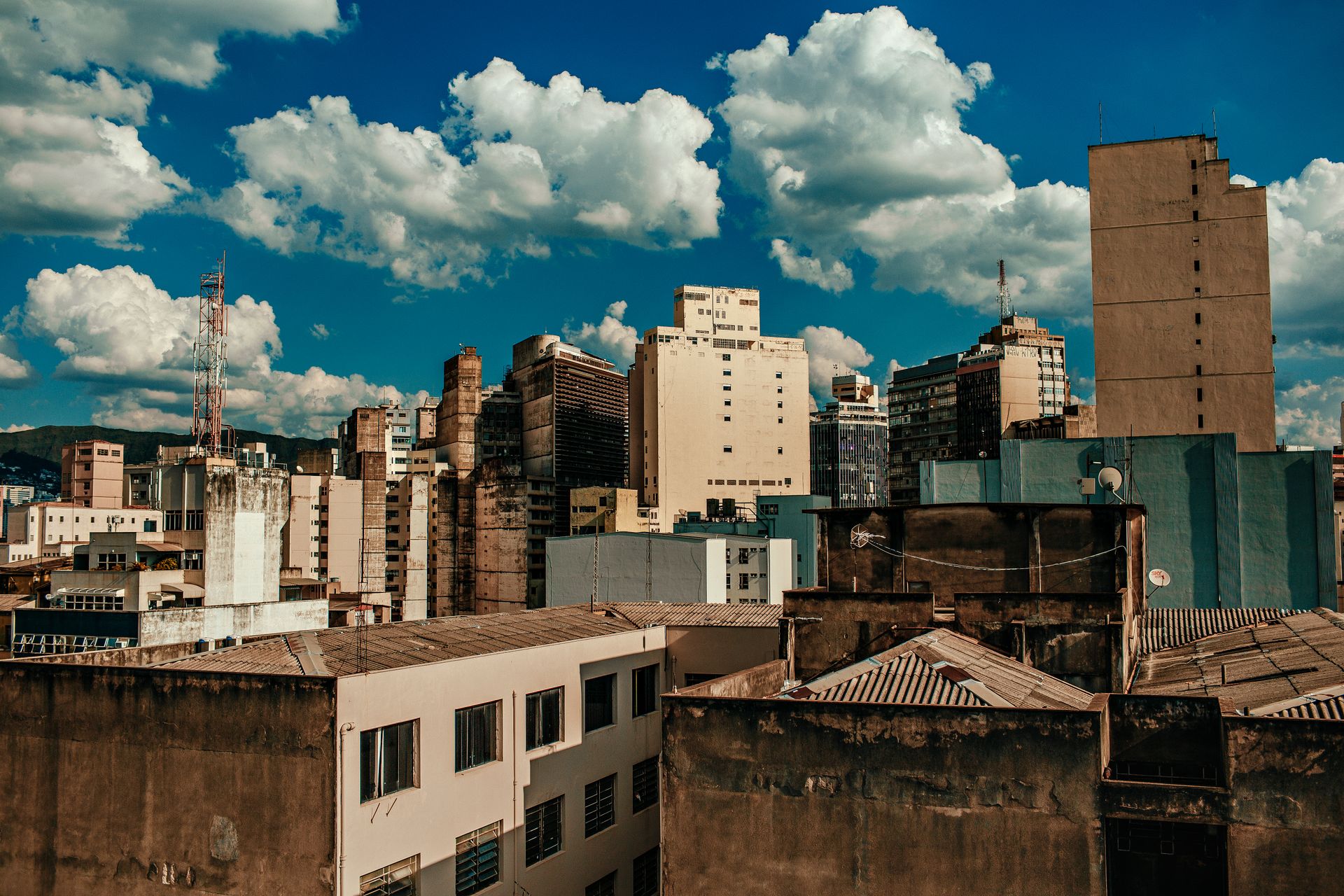 City skyline featuring a mix of old and modern buildings under a vibrant blue sky with clouds.
