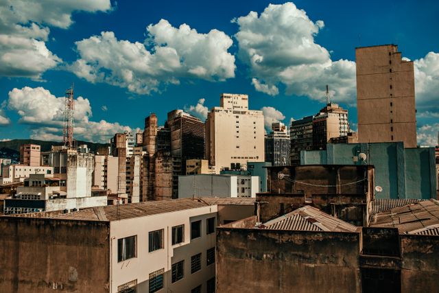 City skyline featuring a mix of old and modern buildings under a vibrant blue sky with clouds.