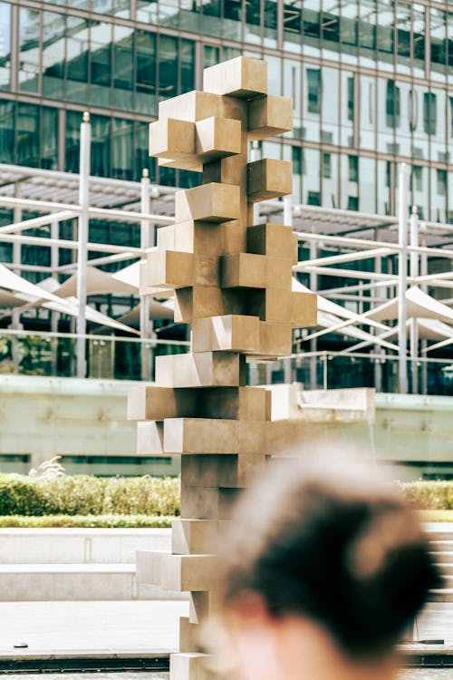 A woman is walking by a sculpture of cubes