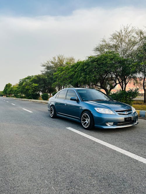 Photo of a Car on an Asphalt Road, and Trees in Background