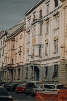 Charming street view of historic European apartment buildings with parked cars, showcasing traditional architecture.