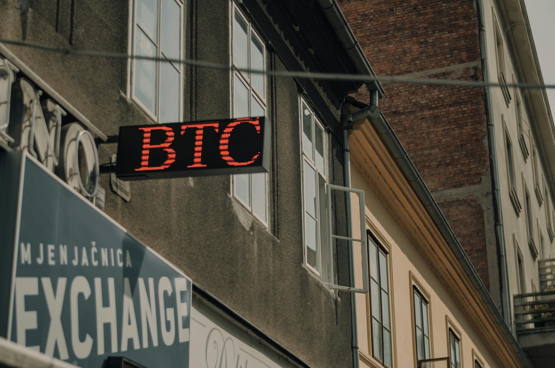 Exterior of a building featuring a prominent BTC and exchange sign, indicating a cryptocurrency location.