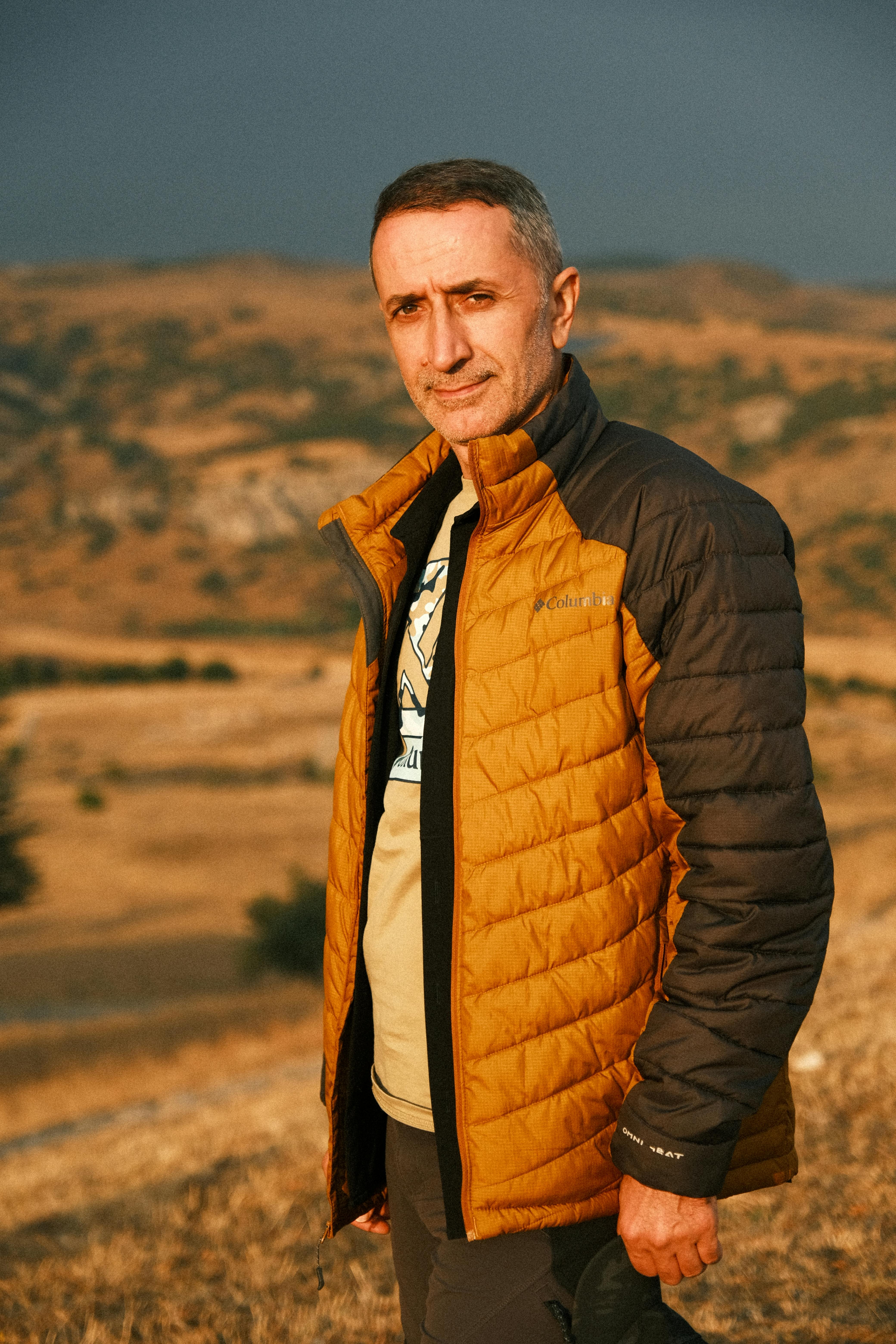 Portrait of a man posing outdoors in an autumn landscape, wearing a stylish jacket.