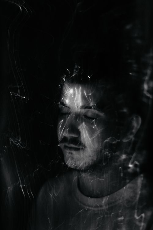 Free A creative black and white portrait of a man with eyes closed, featuring dynamic light patterns. Captured in Bratislava. Stock Photo