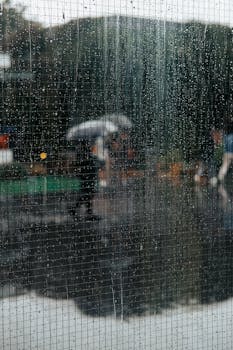 A rainy day in Istanbul view from a window, capturing the blurred figure of a person with an umbrella.