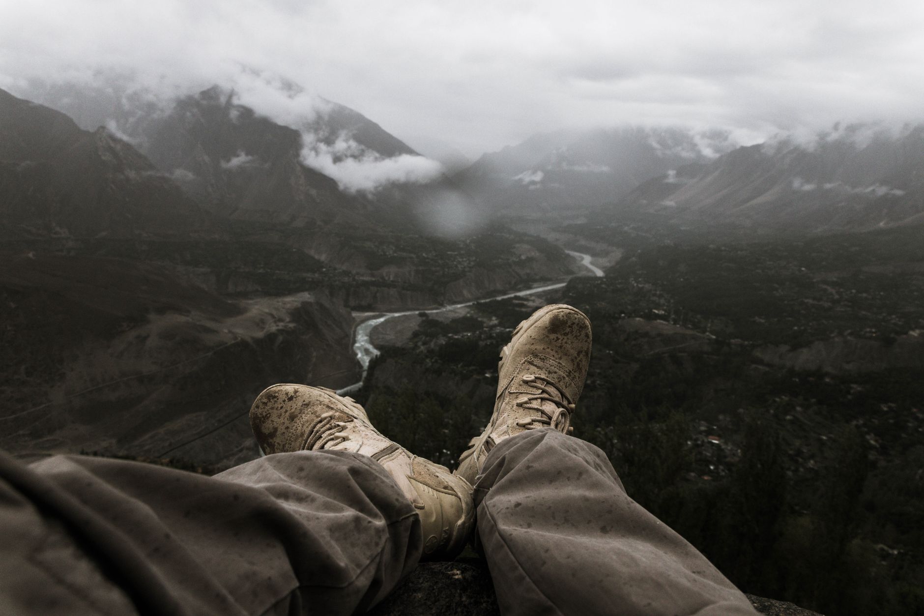 Breathtaking view of a hiker's muddy boots overlooking a misty mountain valley.