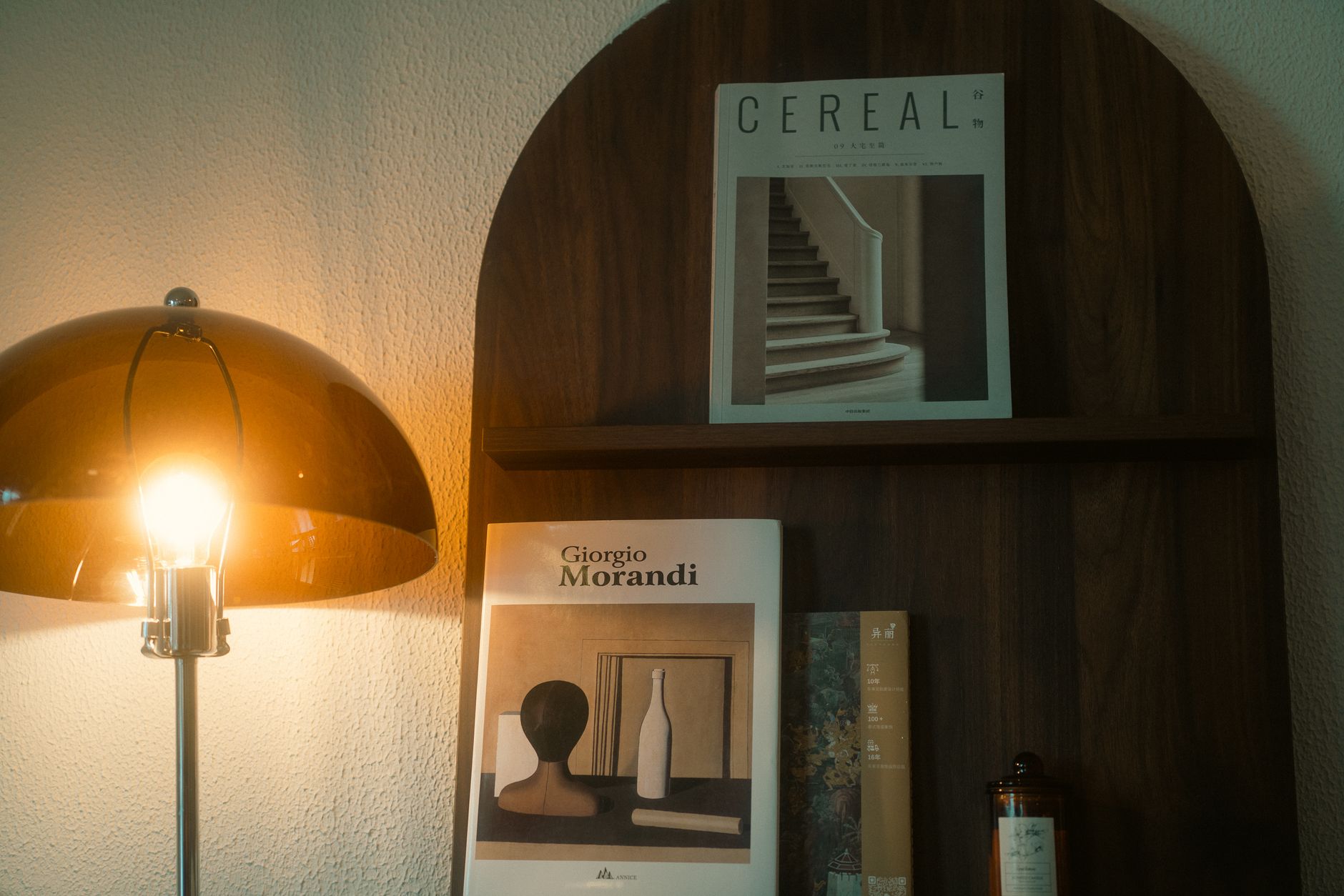 An elegant setup featuring a modern lamp and art books on a wooden shelf, perfect for interior design inspiration.