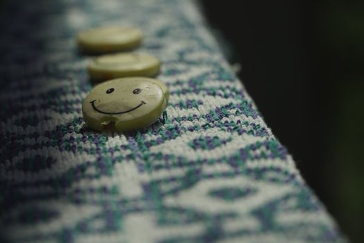 Close-up of smiley face buttons on textured fabric, highlighting craftsmanship and playful design.