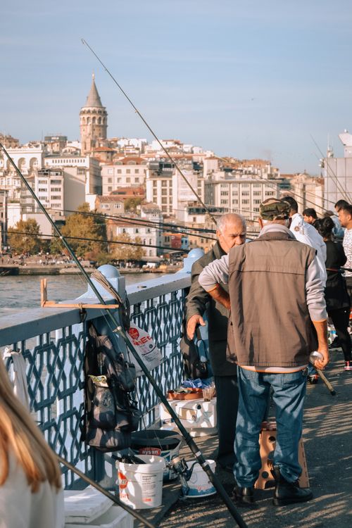 Free Men fishing on Istanbul's Galata Bridge with Galata Tower in view. Stock Photo