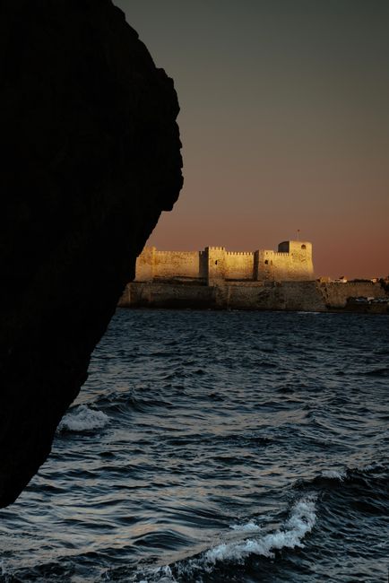 Captivating sunset over the sea with Bozcaada Castle in view.